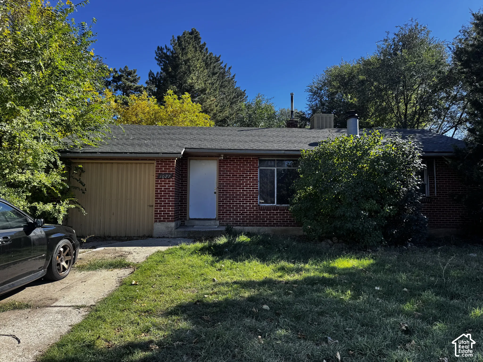 Single-story brick exterior featuring a shingle roof, attached one-car garage, and concrete driveway