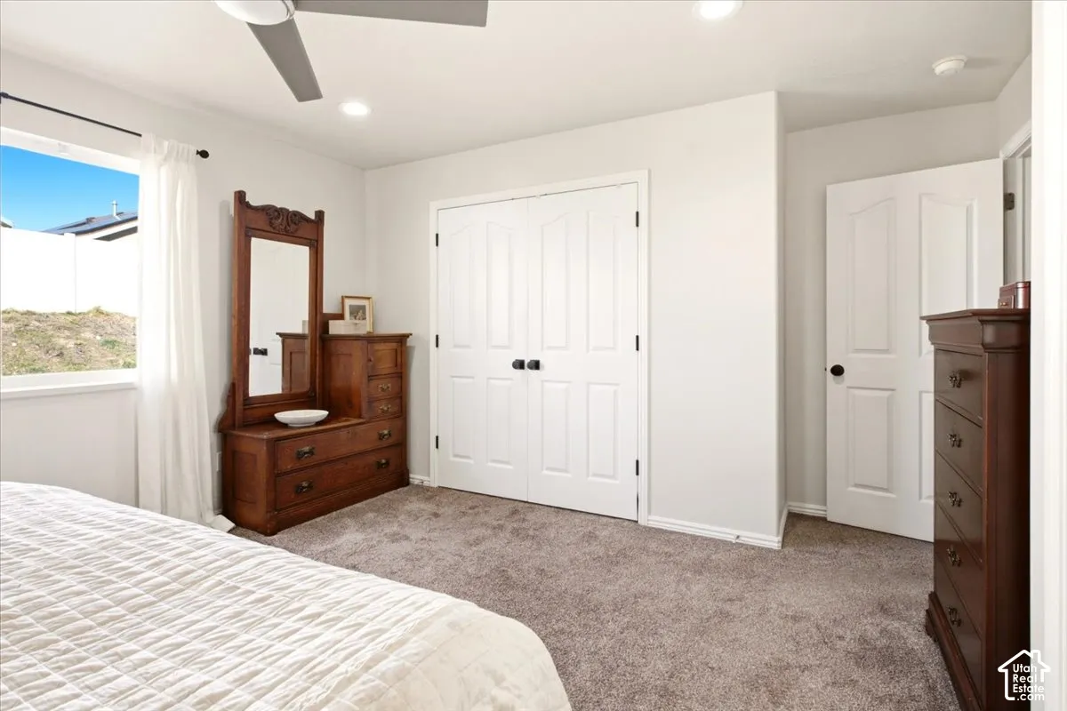 Primary Bedroom, Neutral-toned carpeted flooring, double-door closet with matte black hardware, recessed ceiling lighting, and a multi-blade ceiling fan