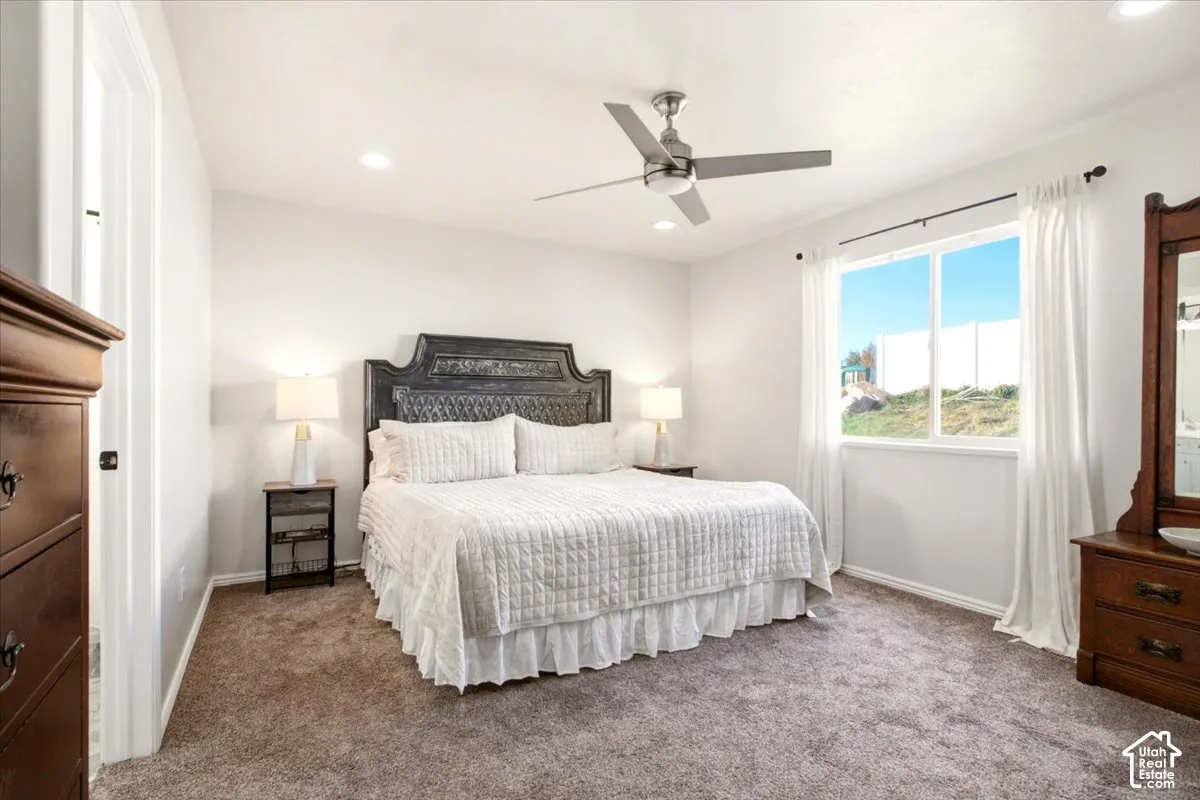 Primary bedroom featuring neutral wall tones, carpeted flooring, a ceiling fan with integrated lighting, and a large window