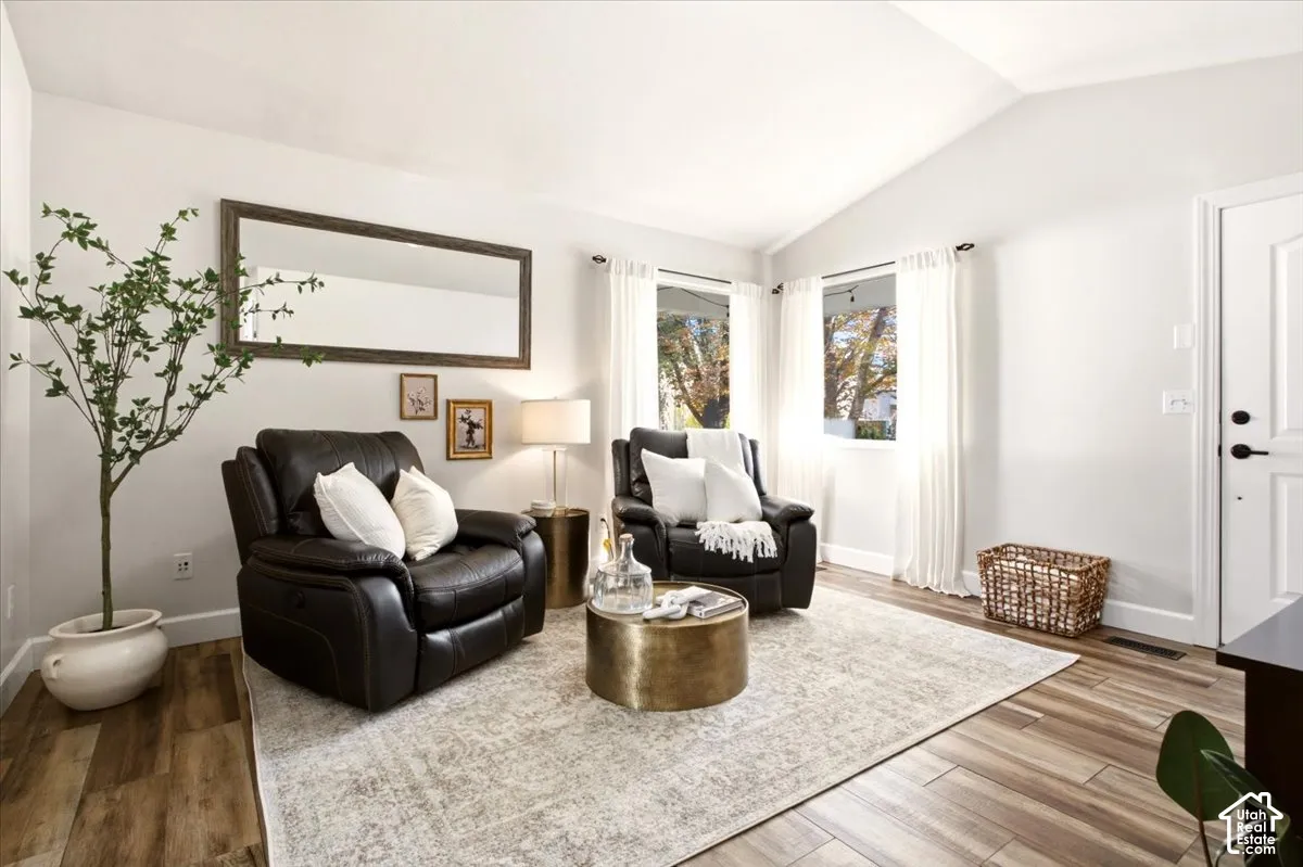 main-level living room highlighting vaulted ceilings, updated flooring, and an open connection to the hallway.