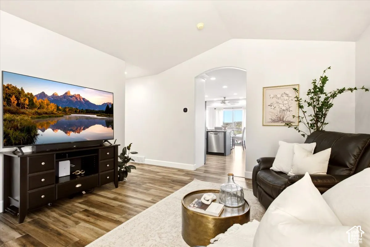 Main-level living room featuring vaulted ceilings, updated flooring, and an arched entryway.