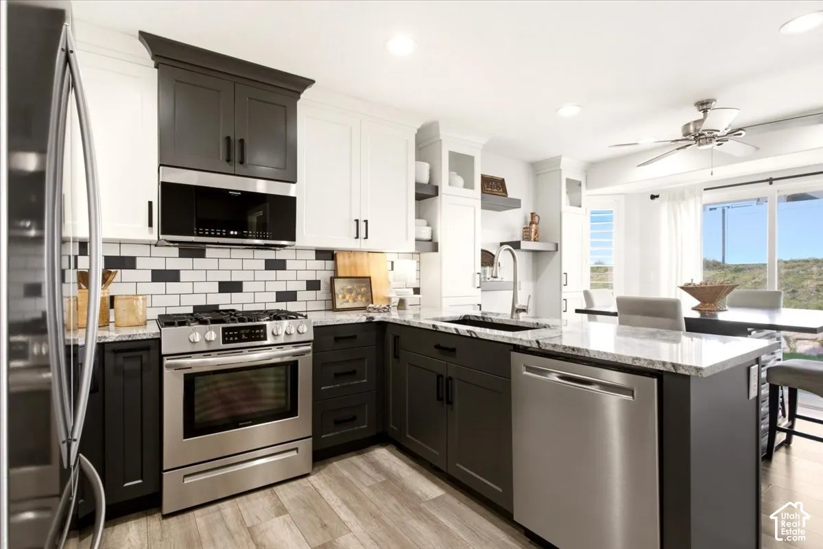 Remodeled kitchen featuring two-tone cabinetry, granite countertops, stainless steel appliances, and updated finishes.