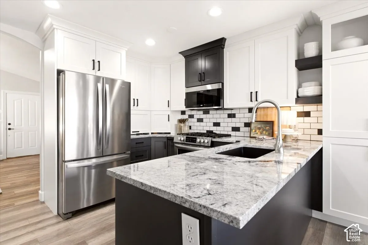 updated kitchen showcasing the center island, contrasting cabinetry, and stainless steel appliances.