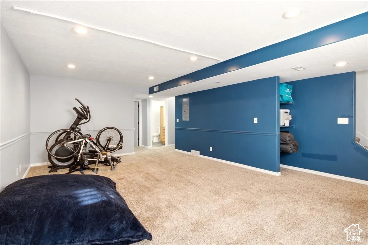 Interior space featuring wall-to-wall carpeting, recessed ceiling lighting, accent wall, and built-in shelving