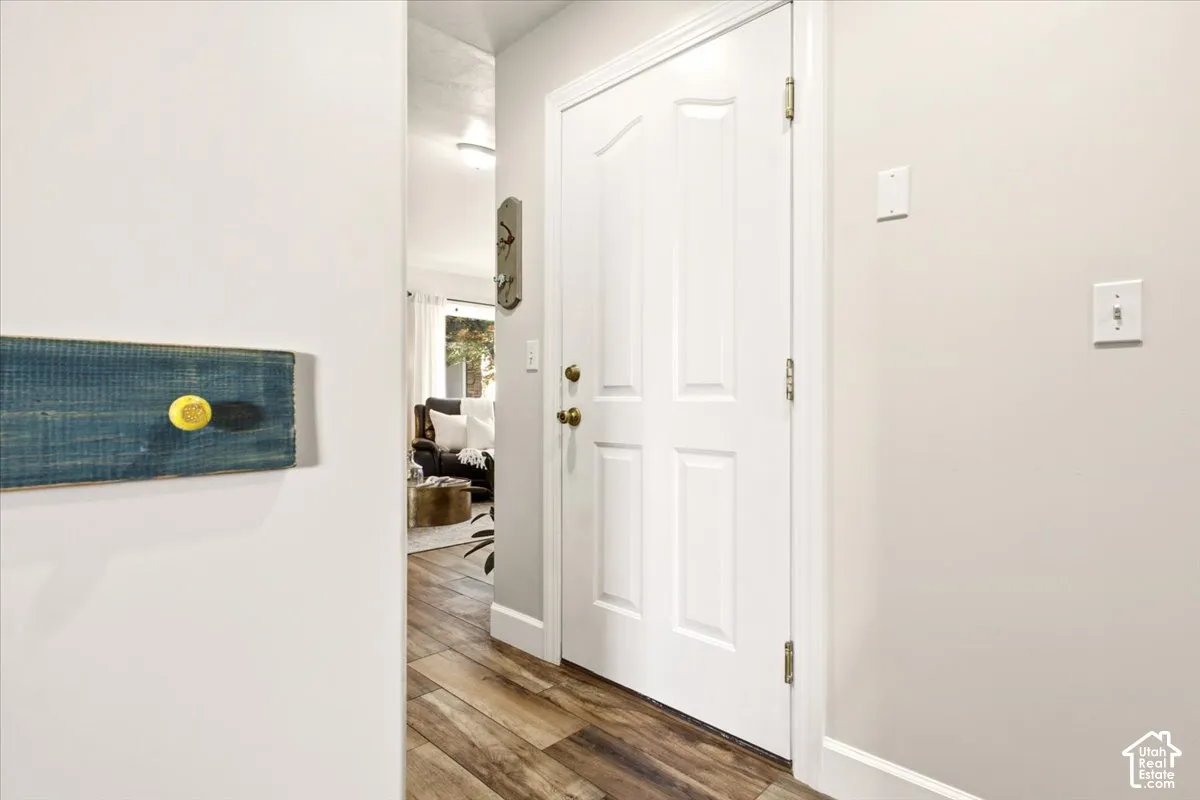 Garage access featuring a four-panel white door with brass-tone hardware and wood-finish flooring