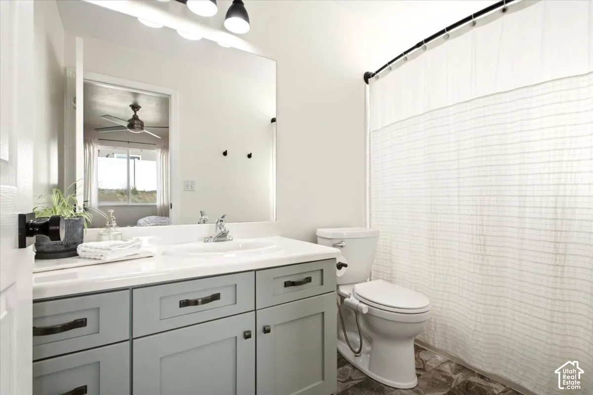 Primary Bathroom featuring a vanity with shaker-style cabinets, countertop-integrated basin, matte black hardware, large wall-mounted mirror, and overhead tri-light fixture