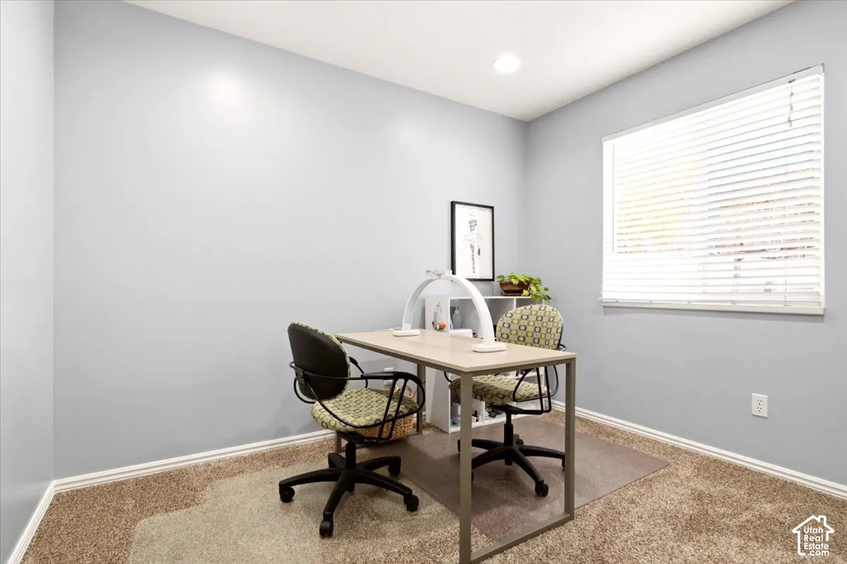 Neutral-toned interior room featuring wall-to-wall carpeting, recessed ceiling lighting, and a window with horizontal blinds