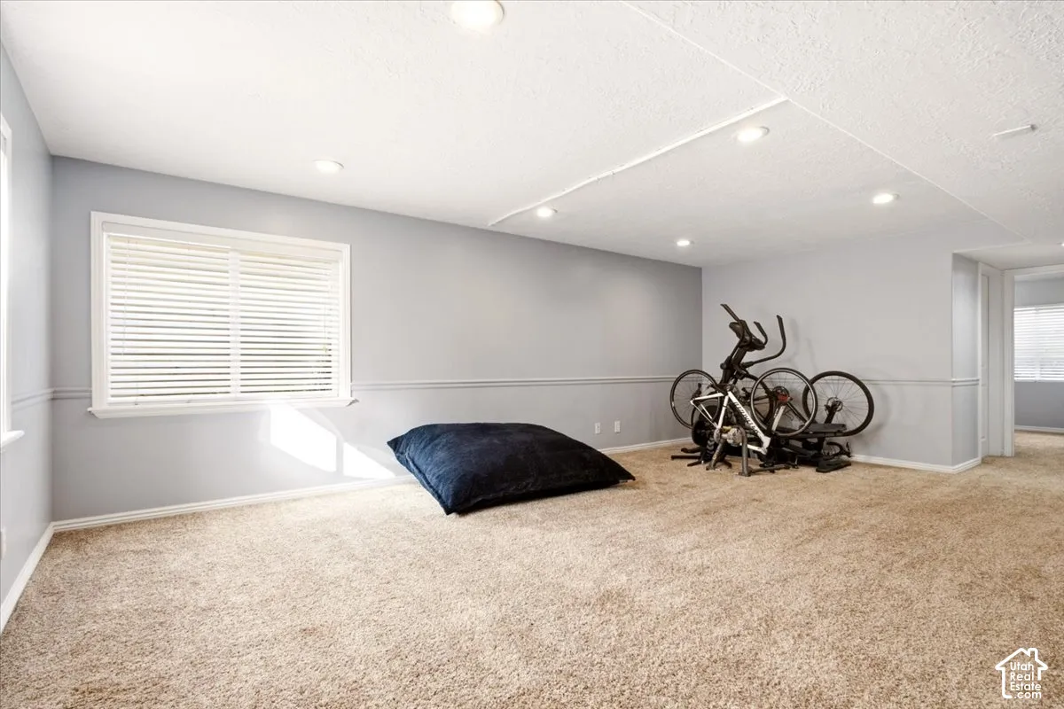 Neutral-toned interior space featuring recessed ceiling lighting, wall-to-wall carpeting, chair rail molding, and a double-pane window with horizontal blinds