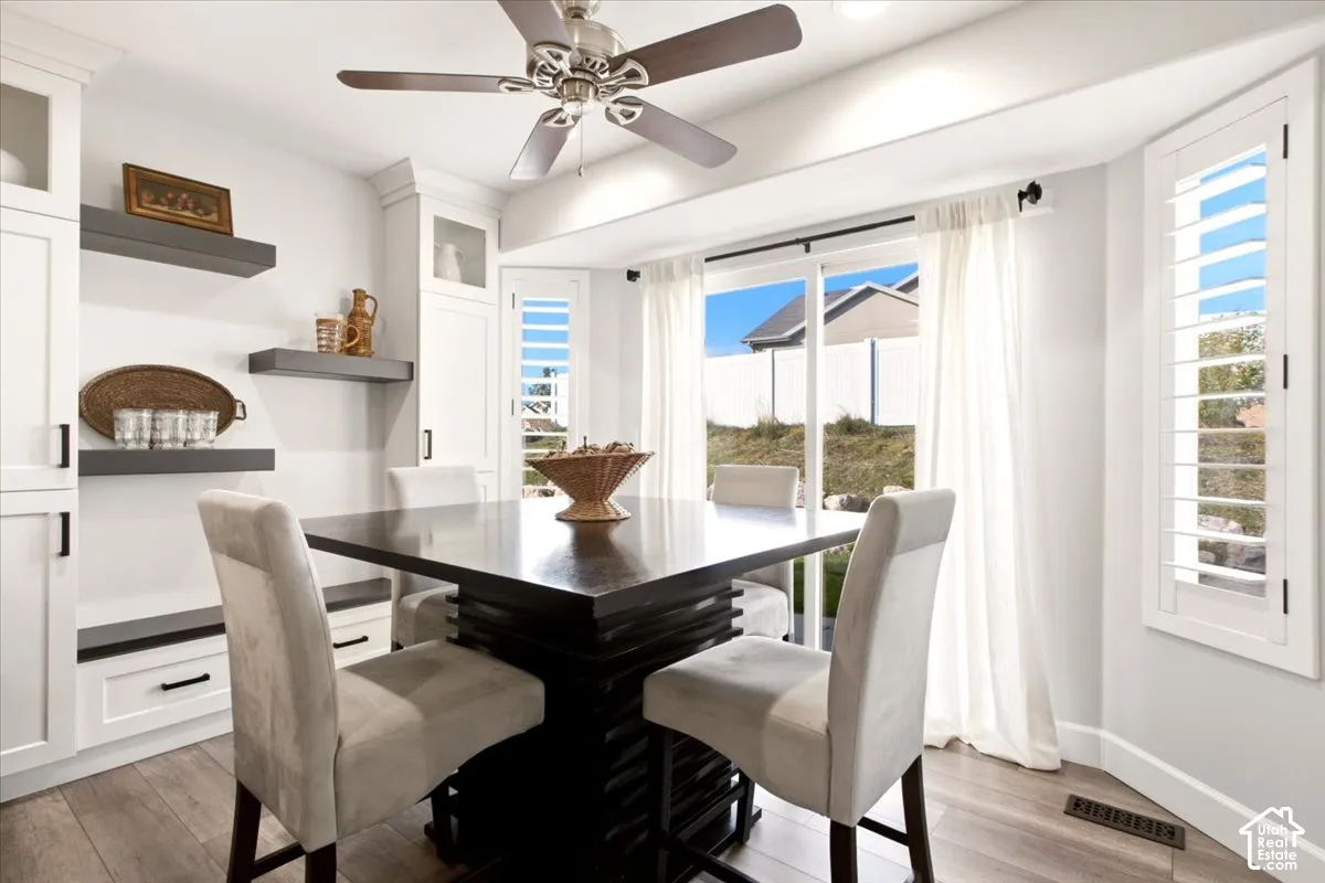 Dining area featuring built-in shelving, updated flooring, and large windows overlooking the backyard.