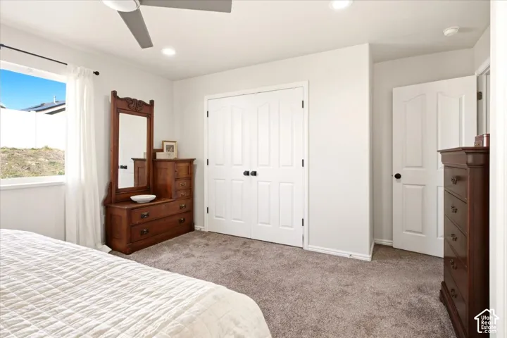 Primary Bedroom, Neutral-toned carpeted flooring, double-door closet with matte black hardware, recessed ceiling lighting, and a multi-blade ceiling fan