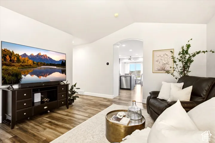 Main-level living room featuring vaulted ceilings, updated flooring, and an arched entryway.