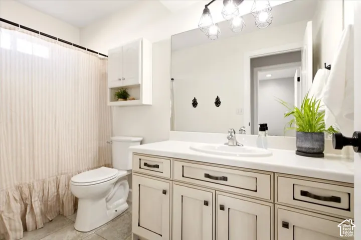 Bathroom featuring a dual-toned vanity with neutral cabinetry, an integrated sink with a solid-surface countertop, a large wall-mounted mirror, and decorative overhead pendant lighting
