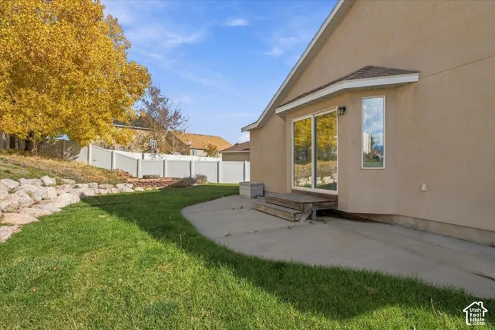 Exterior stucco finish with concrete patio, sliding glass doors, and perimeter privacy fencing