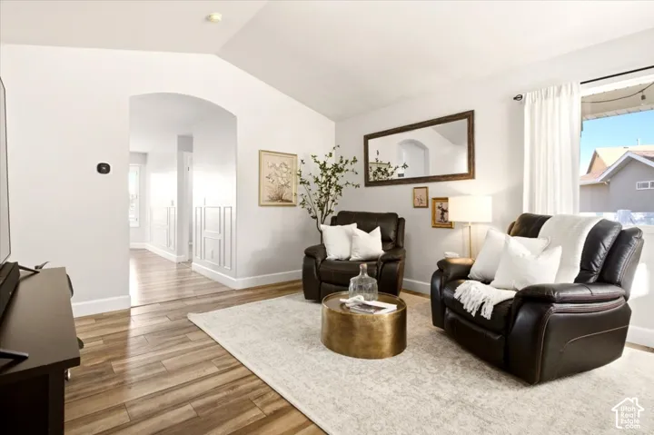 Bright main-level living room with vaulted ceilings, updated flooring, and natural light.