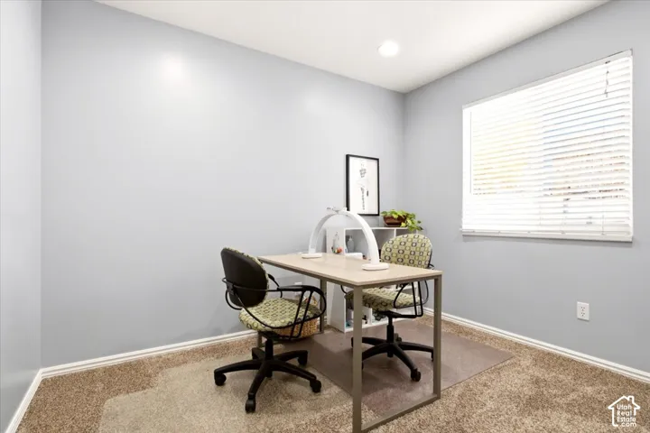 Neutral-toned interior room featuring wall-to-wall carpeting, recessed ceiling lighting, and a window with horizontal blinds
