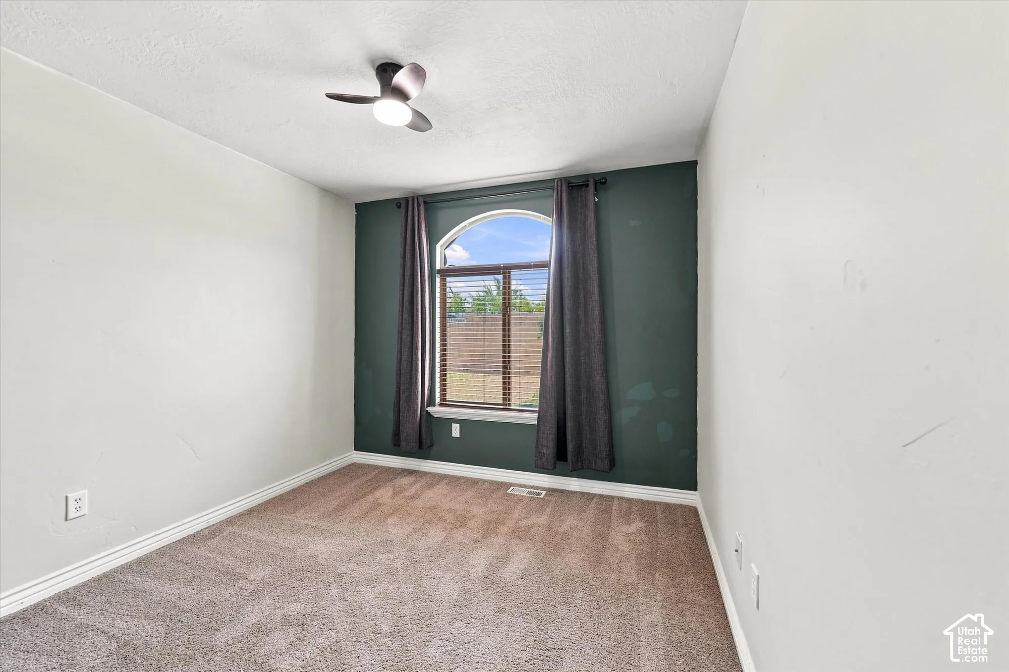 Room featuring wall-to-wall carpeting, an arched window, and a three-blade ceiling fan with integrated lighting