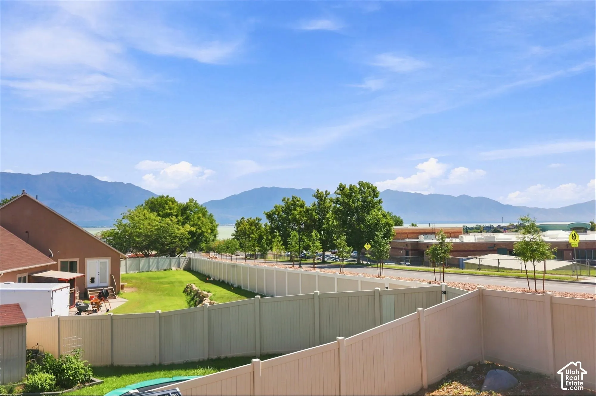 Backyard featuring a manicured lawn, perimeter vinyl fencing, and mountain scenery