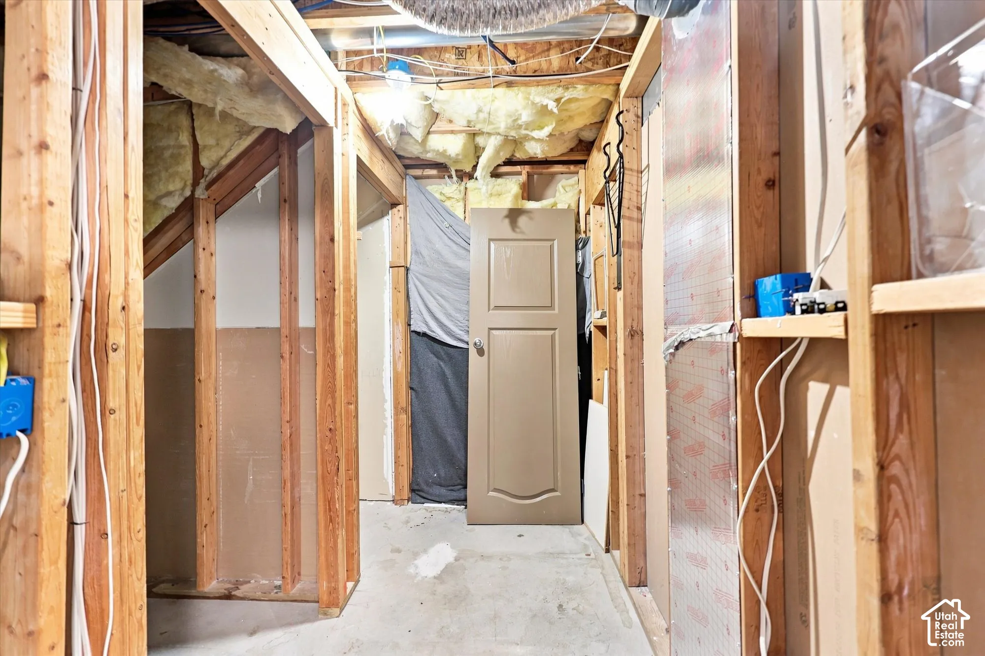 Unfinished space featuring exposed wood stud framing, concrete flooring, and insulated ceiling joists
