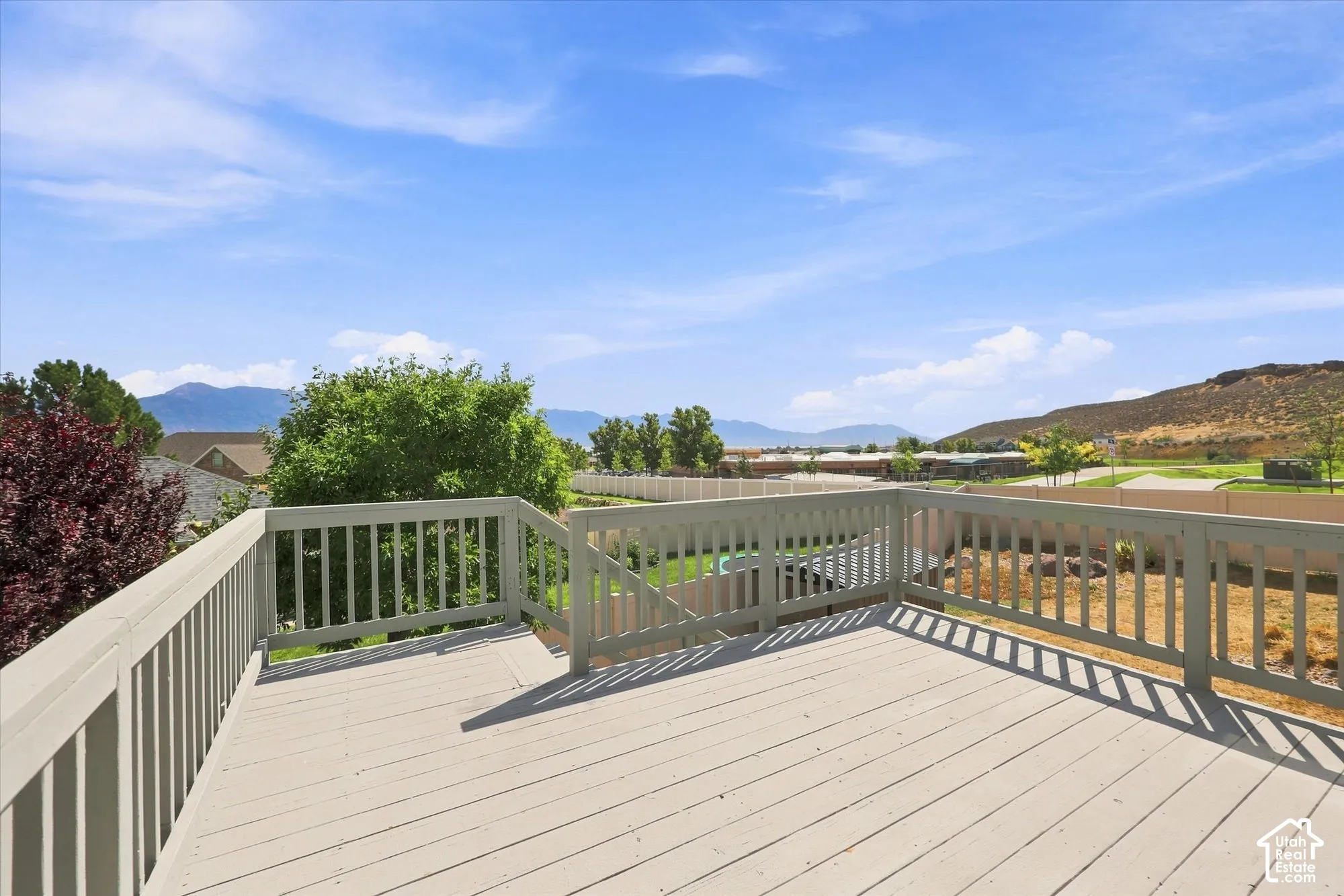 Elevated wooden deck featuring perimeter railing, stair access, and mountainous terrain scenery
