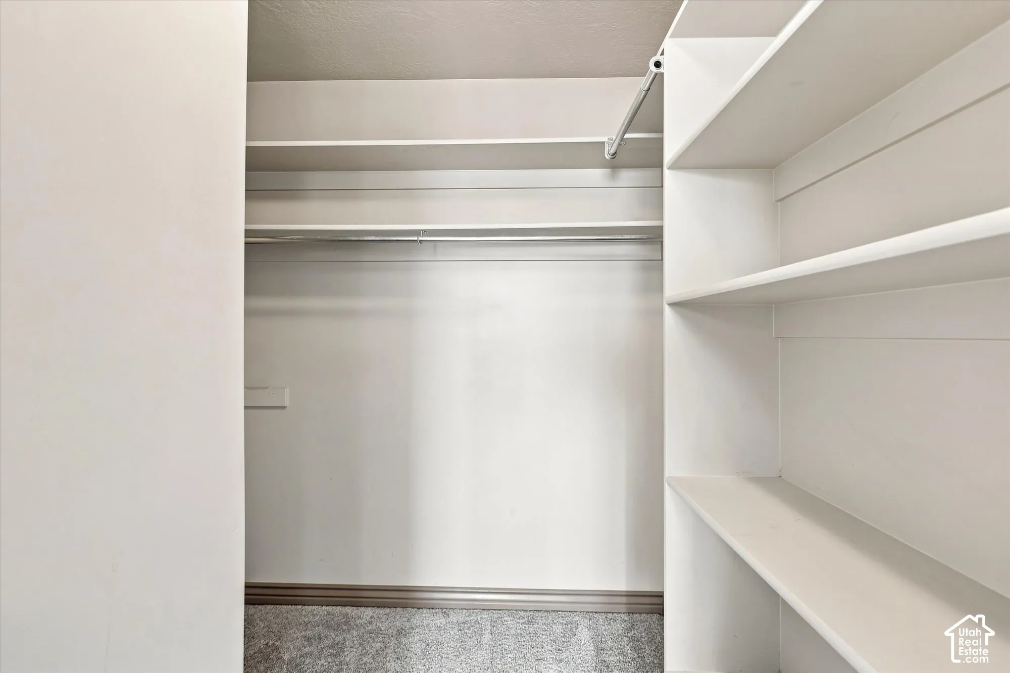 Built-in white shelving, integrated clothing rods, and wall-to-wall carpeting