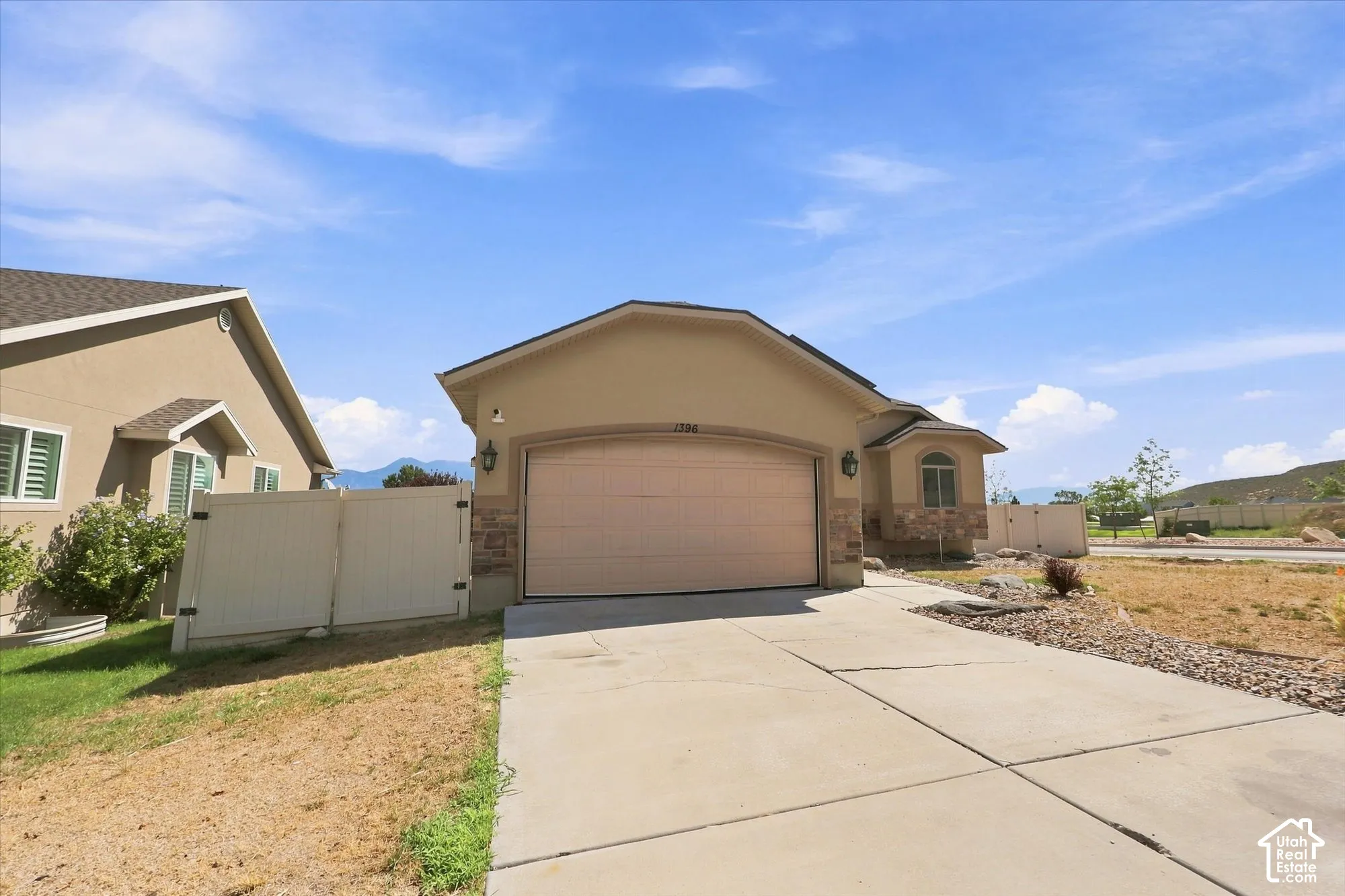 Attached two-car garage with arched entry, stone veneer accents, stucco siding, and a concrete driveway