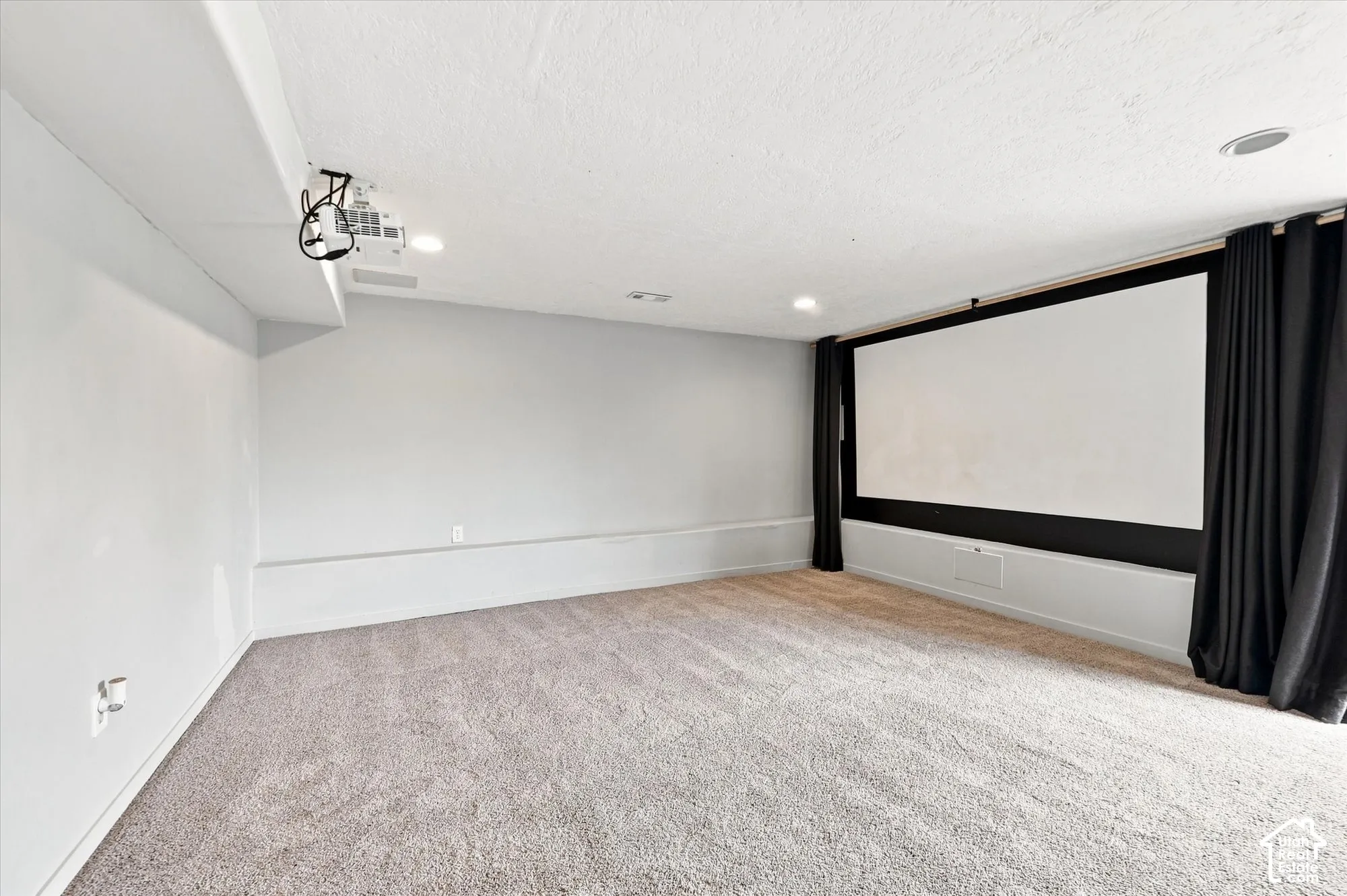 Recessed ceiling lighting, wall-mounted projection screen, ceiling-mounted projector, and neutral carpeting