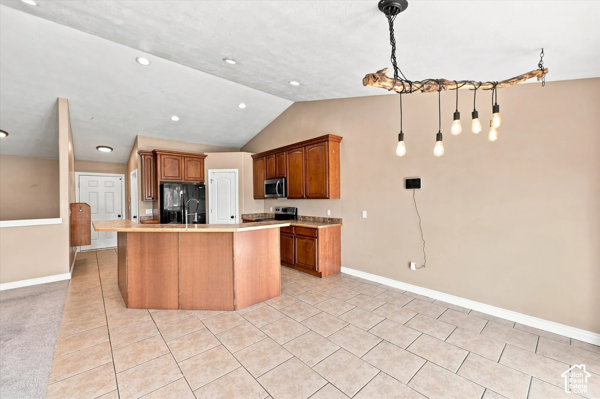 Vaulted ceiling, ceramic tile flooring, kitchen cabinetry with laminate countertops, and a custom multi-bulb light fixture