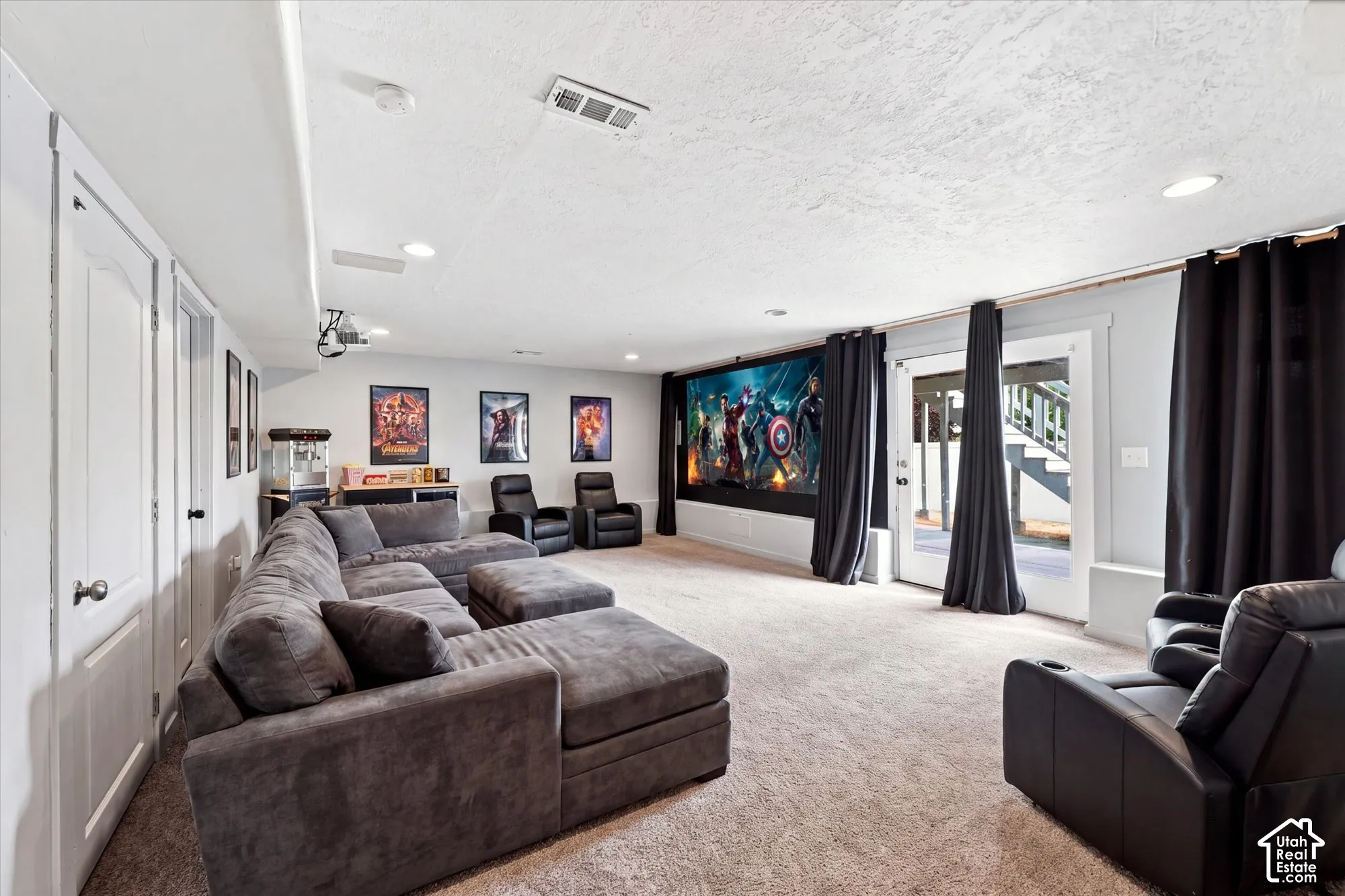 Interior space featuring a large-format projection screen, recessed ceiling lighting, wall-to-wall carpeting, and a glass-paneled door with exterior access