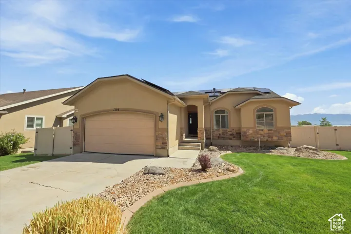 Stucco exterior with stone veneer accents, arched windows, attached garage, rooftop solar panels, and landscaped front yard