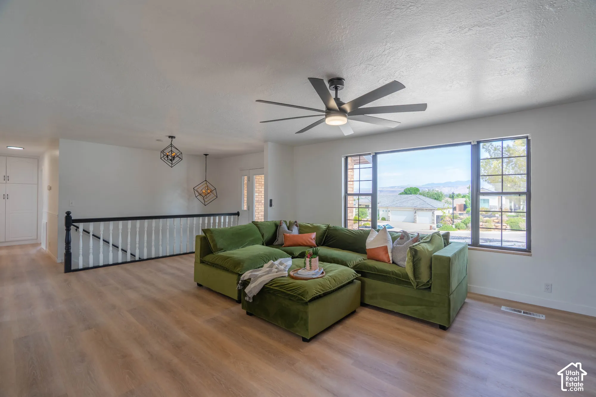 Wood-finish flooring, ceiling fan with integrated lighting, expansive window, staircase with railing, and built-in cabinetry