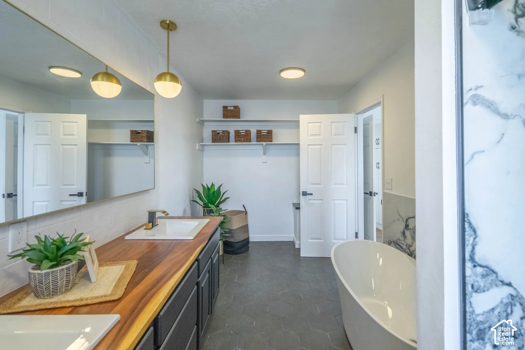 Dual vanity with a wood-finish countertop, undermount sinks, and wall-mounted lighting