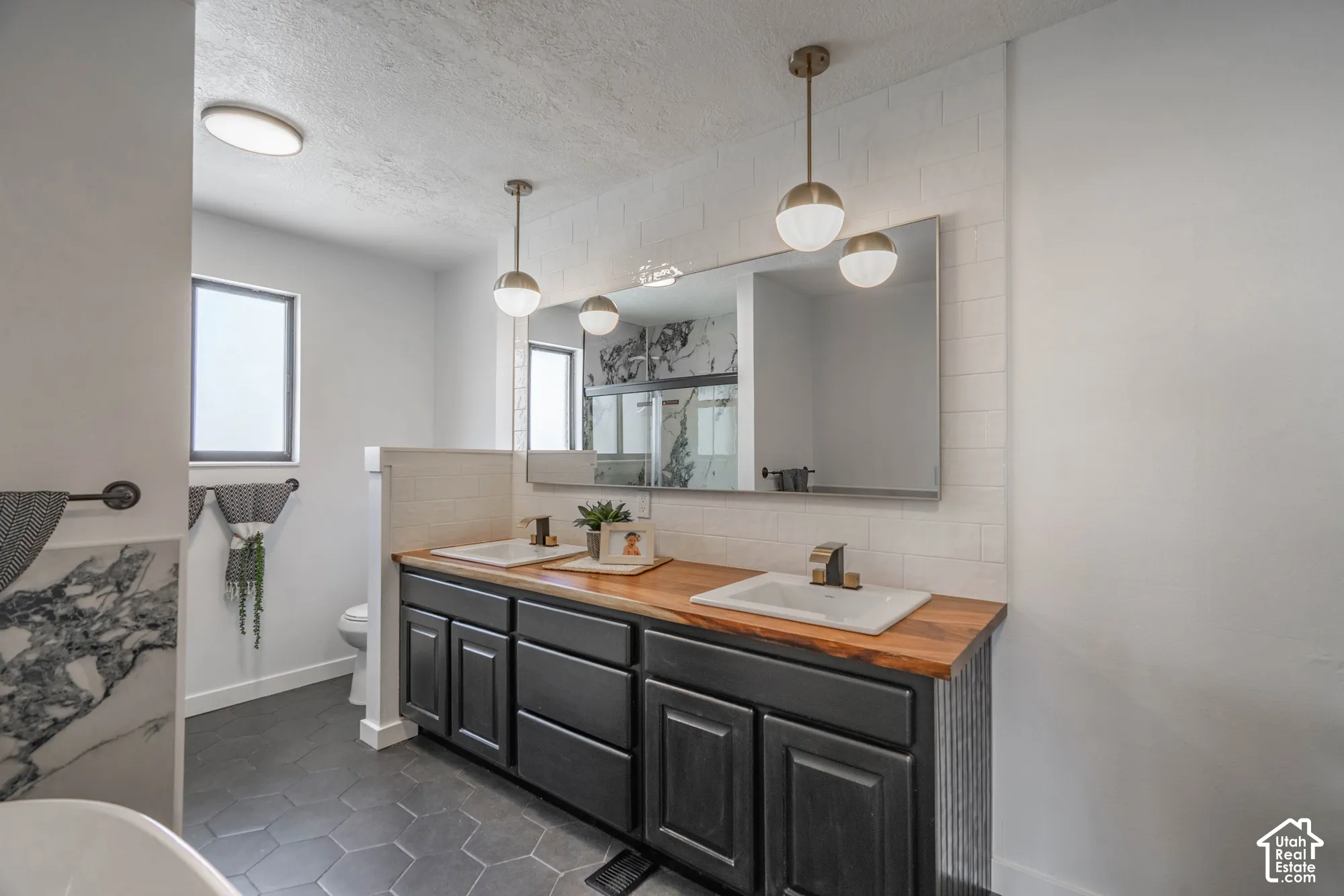 Dual vanity with wood-finish countertop, undermount sinks, and dark cabinetry