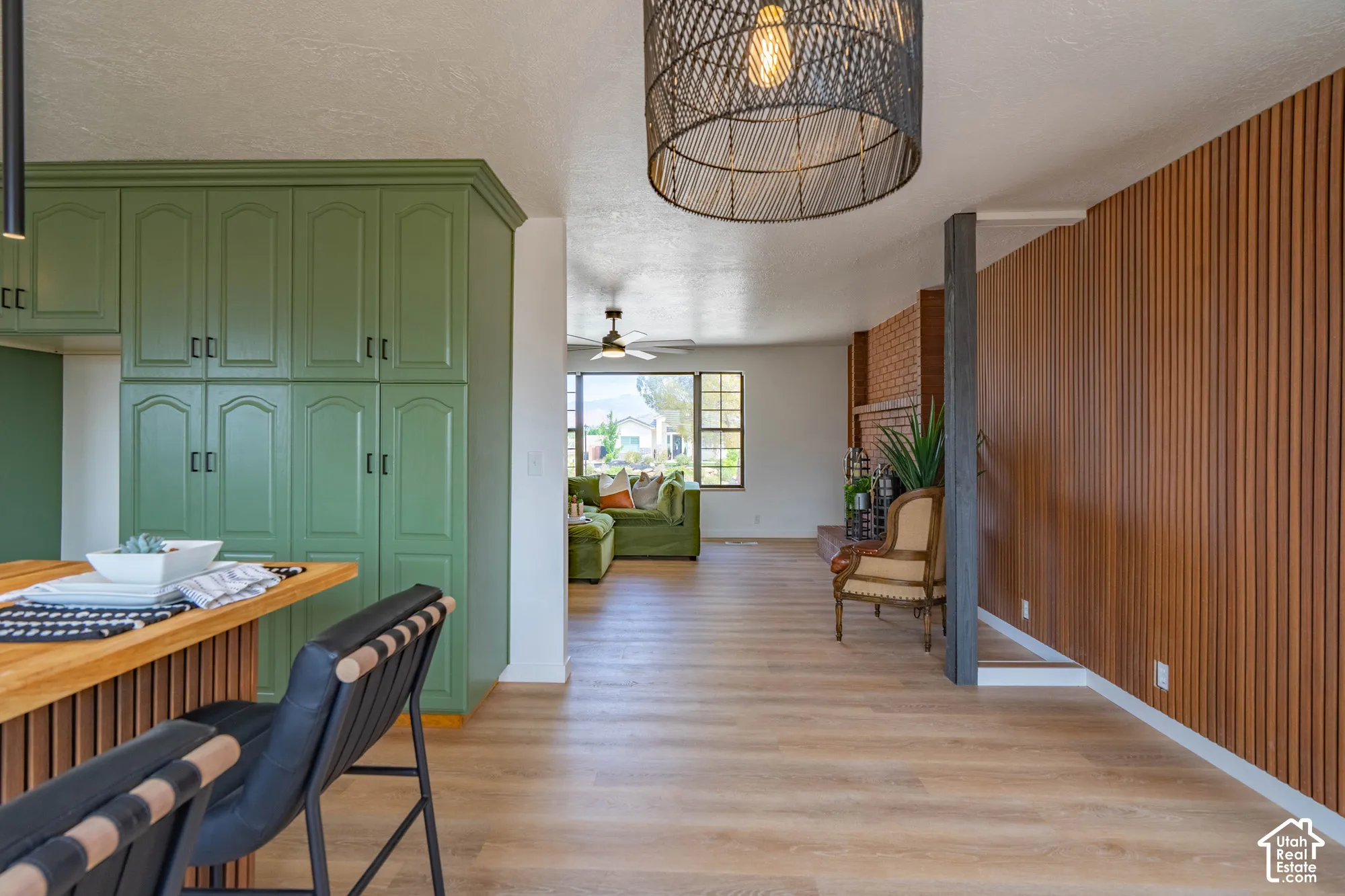 Expansive wood-finish flooring, custom green cabinetry, and a slatted wood accent wall