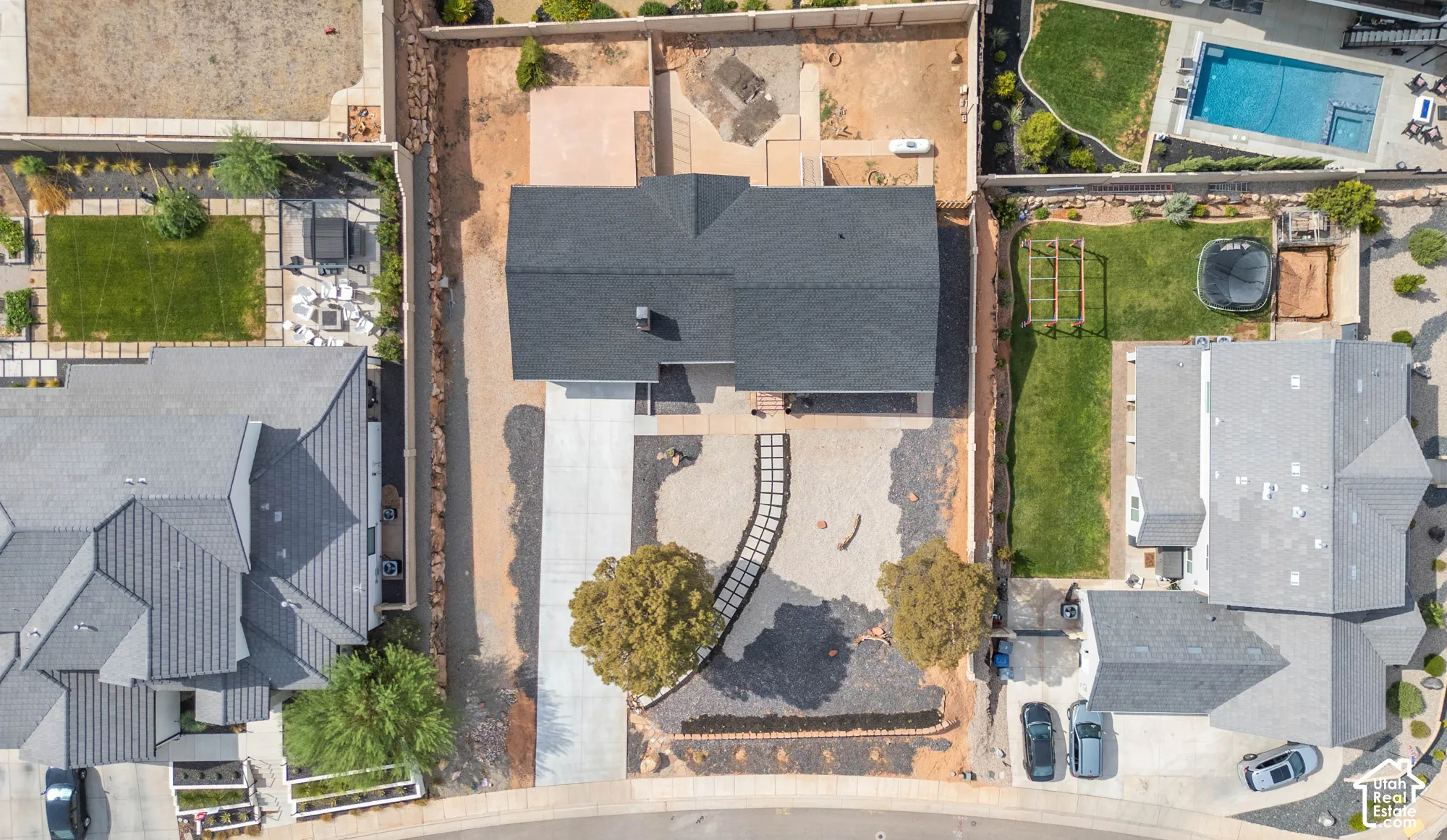 Modern residence with a dark-pitched roof, an extended paved driveway, a curved stone walkway, and mature landscaping