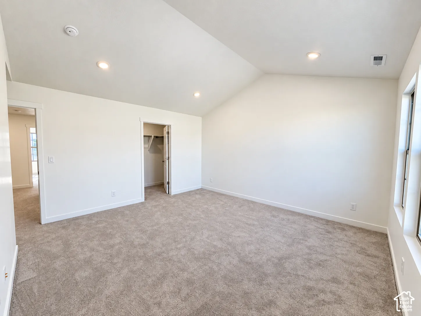 Vaulted ceilings, neutral carpeting, recessed lighting, and a built-in walk-in closet