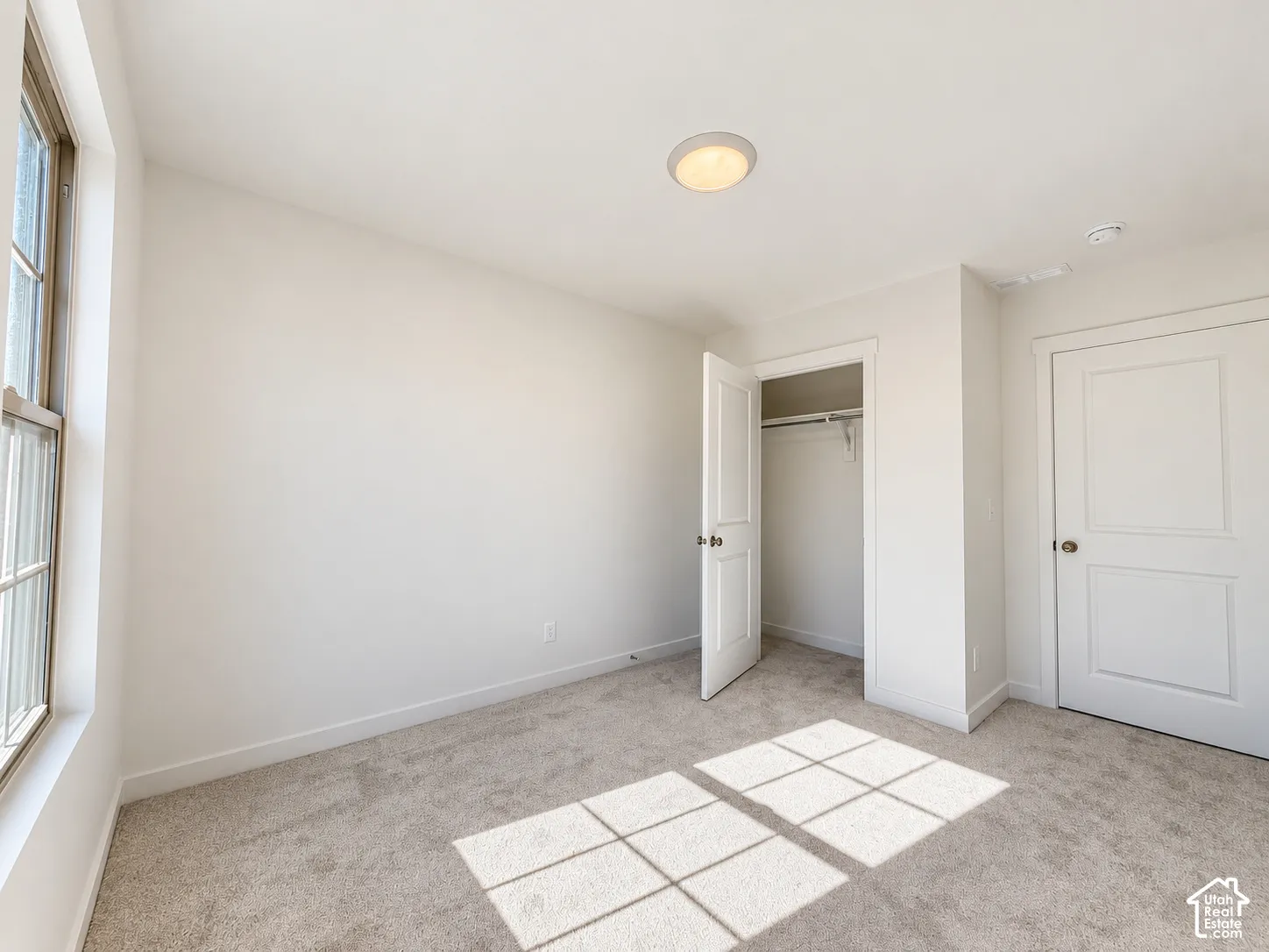 Neutral wall palette featuring plush carpeting, a single-hung window, a walk-in closet with built-in shelving, and a two-panel interior door