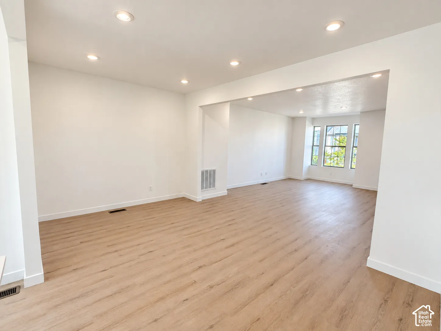 Open floor plan featuring wood-finish flooring, recessed lighting, and large windows with natural illumination