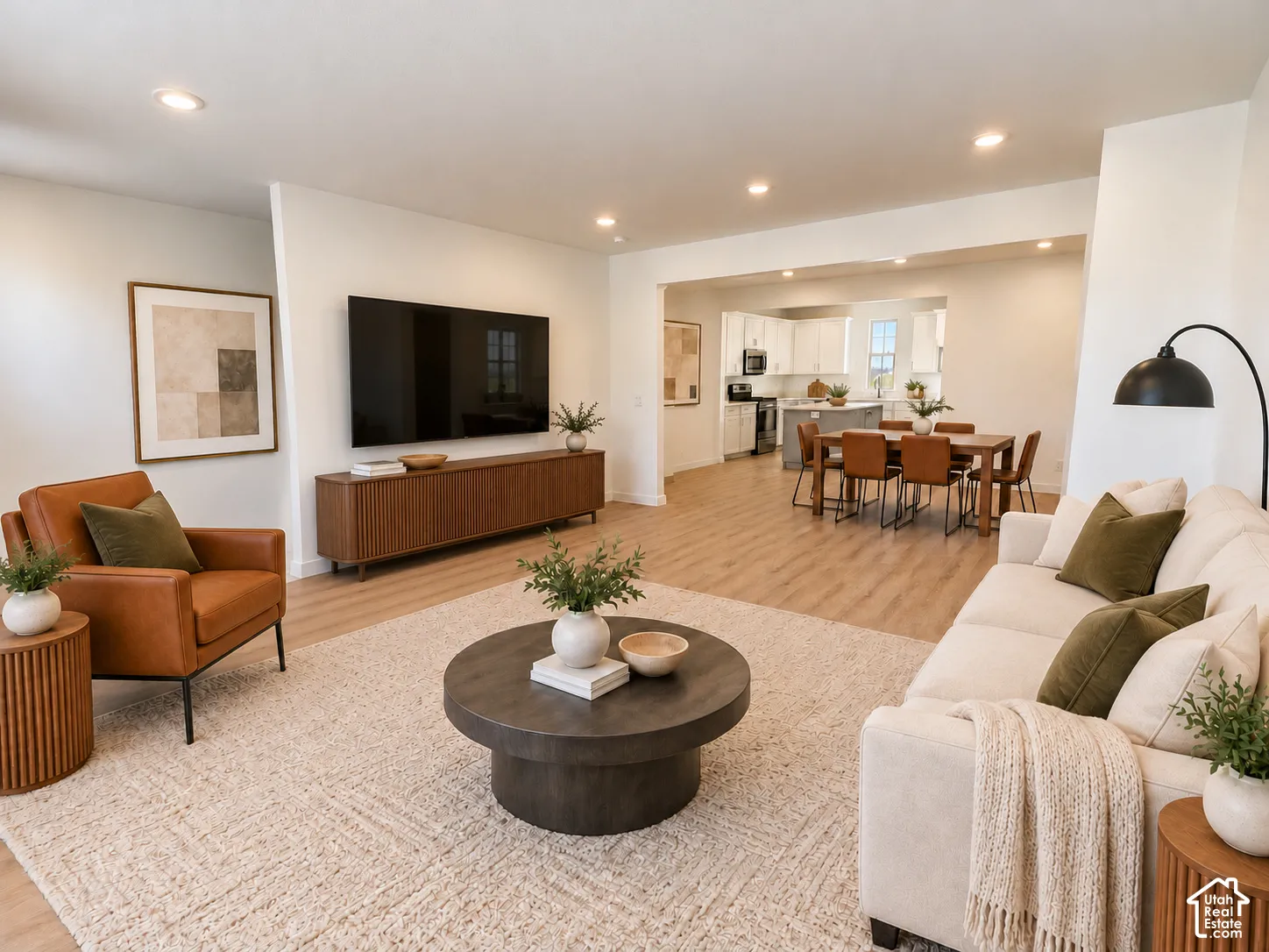 Open-concept living space featuring wood-finish flooring, recessed lighting, and white cabinetry in the kitchen area