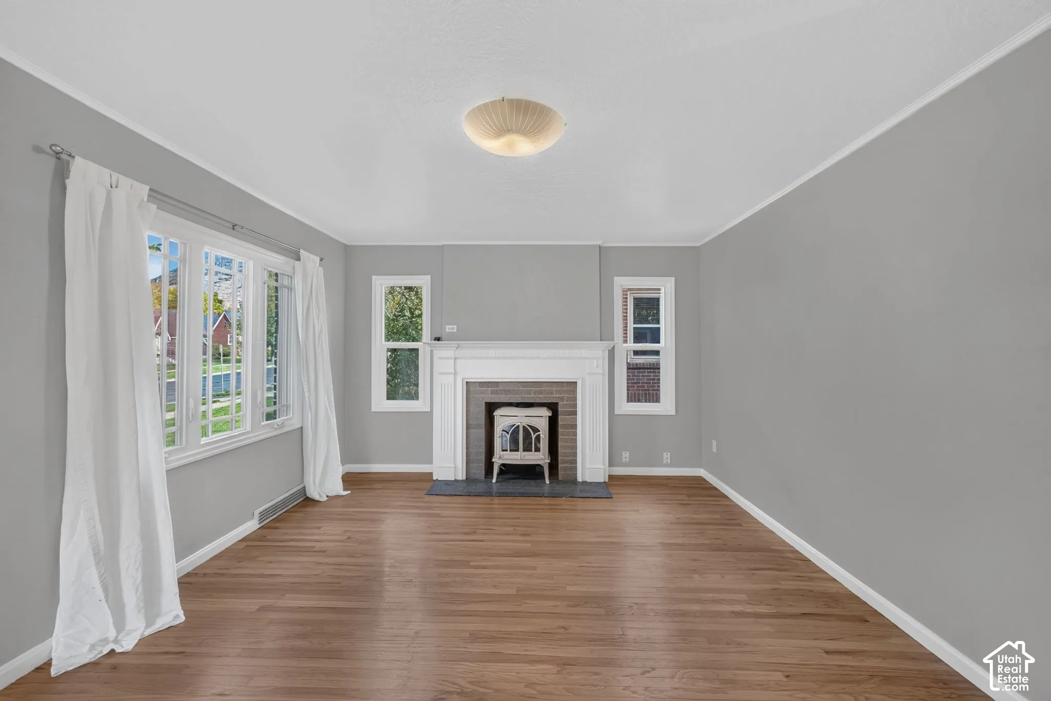 Living area featuring wood-finish flooring, a white mantel fireplace with a decorative tile surround, multi-pane windows, and a flush-mount ceiling fixture