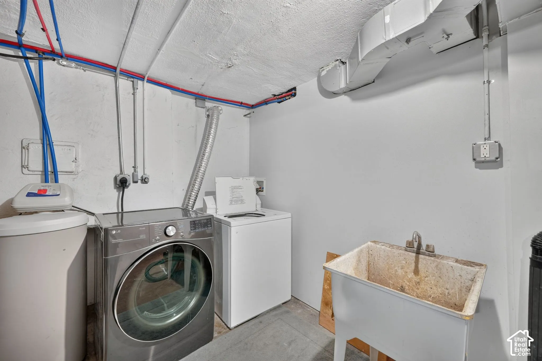 Utility area featuring a front-loading washer, top-loading dryer, basin sink with dual-handle faucet, and integrated water treatment system
