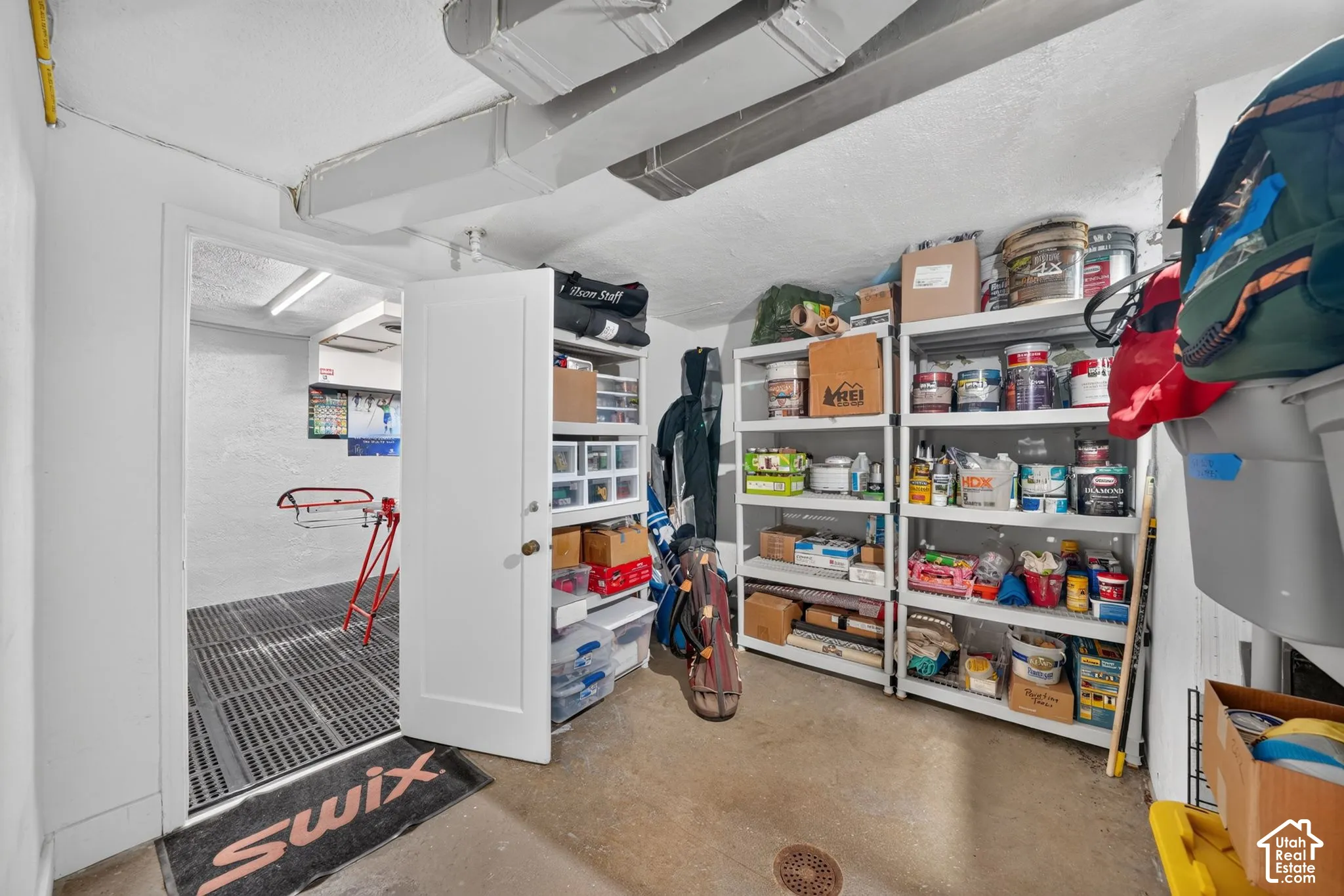 Concrete flooring, textured ceiling surfaces, and open-concept utility area featuring a drainage system and painted wall finishes