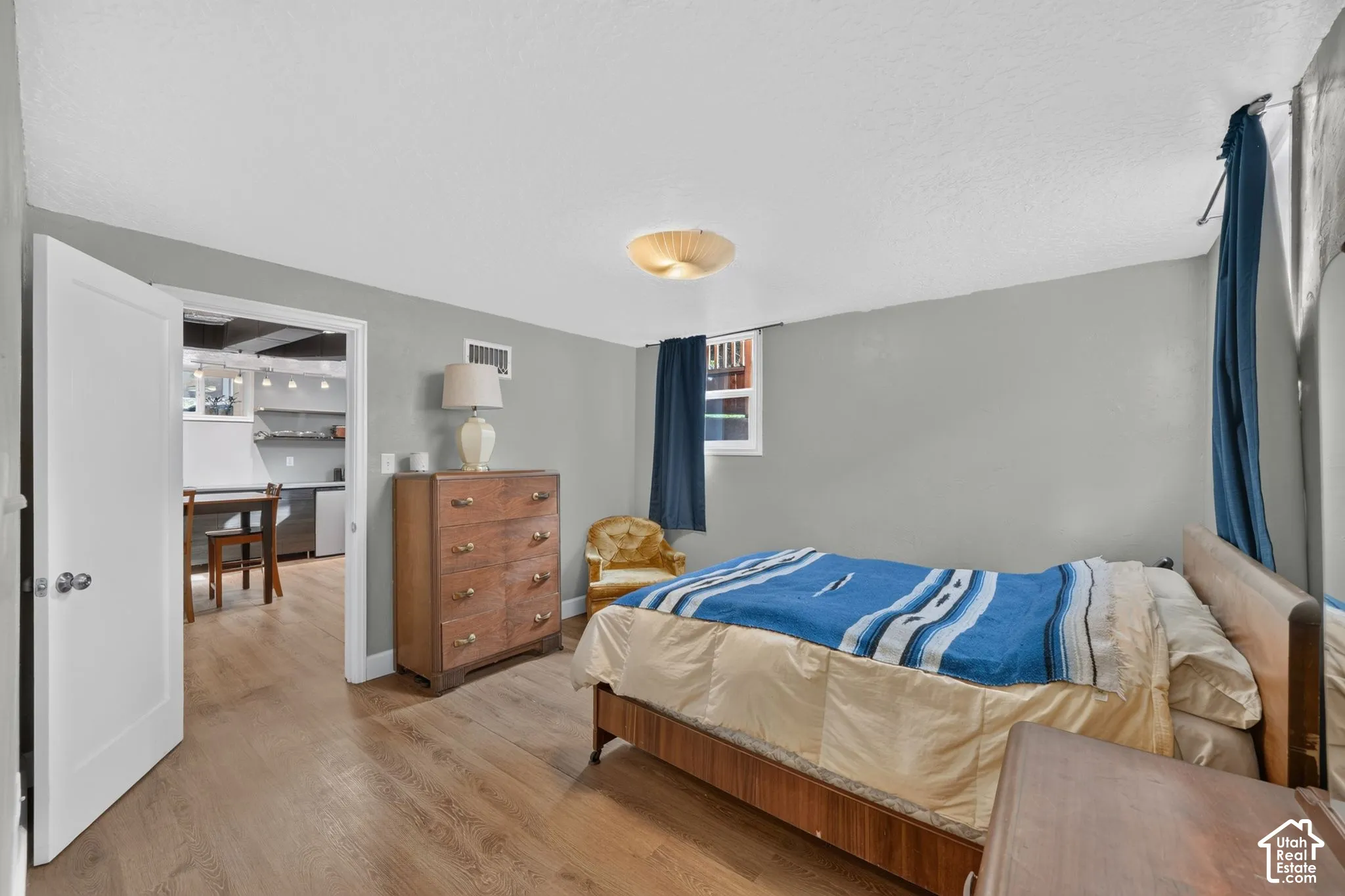 Room featuring wood-finish flooring, neutral wall paint, a flush-mount ceiling light fixture, and a white interior door