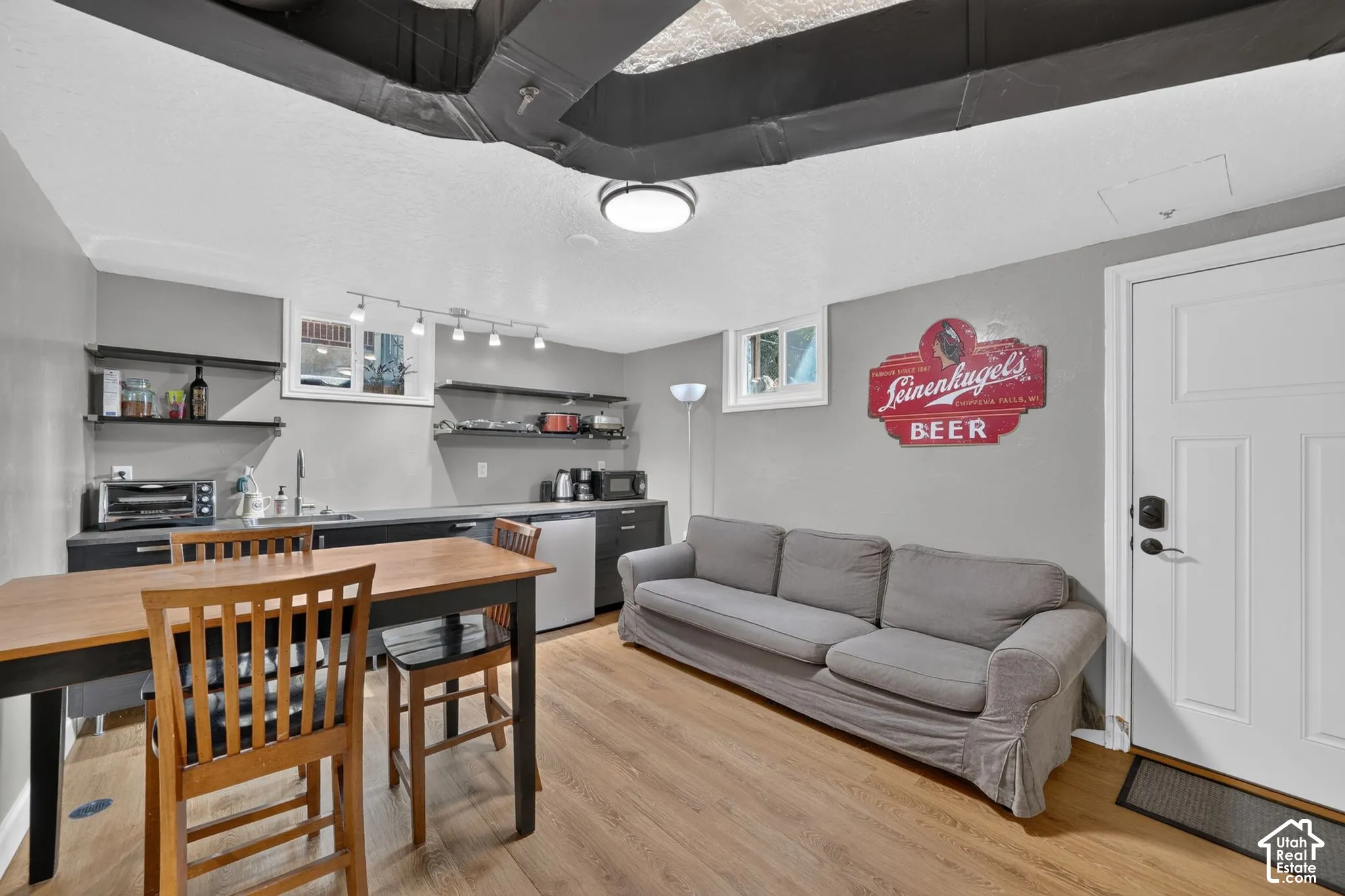 Kitchenette featuring dark cabinetry, open shelving, wood-finish flooring, and exposed ceiling ductwork