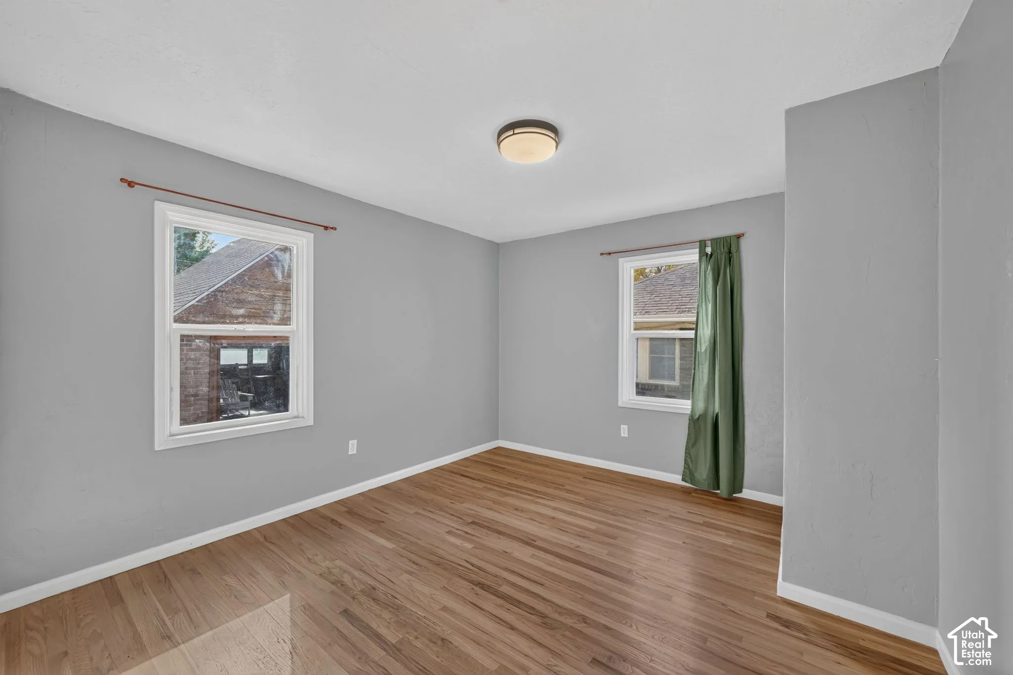 Interior space featuring wood-finish flooring, neutral wall tones, two double-pane windows, and a circular flush-mount ceiling light