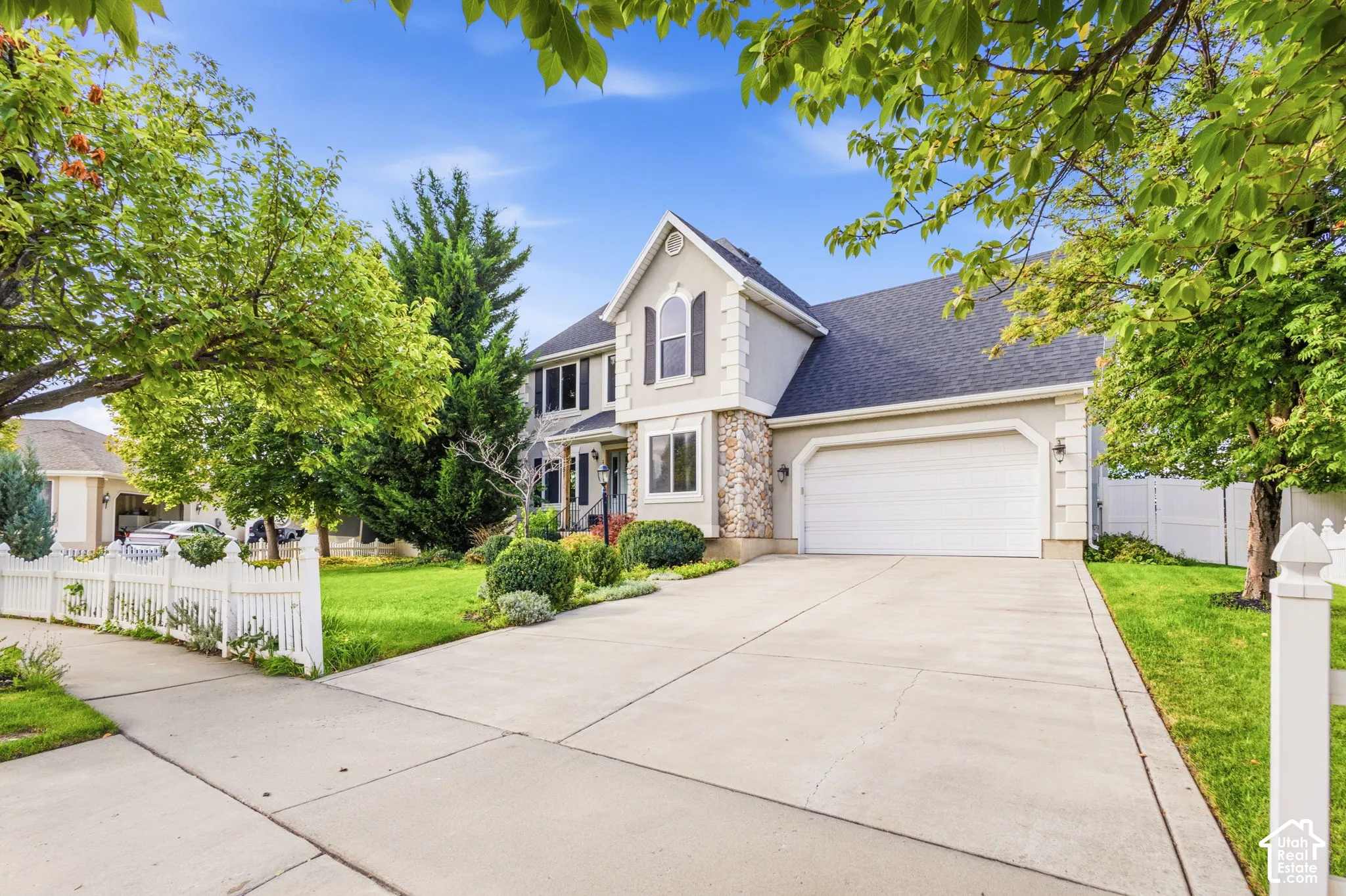 Two-story exterior featuring stone veneer accents, arched window detailing, shutter-style window treatments, and an attached two-car garage