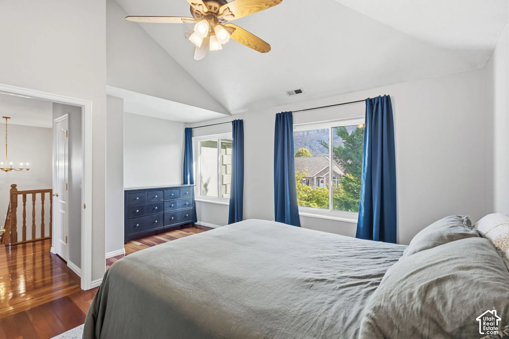 Vaulted ceiling, wood-finish flooring, and multiple dual-pane windows with integrated mountain and landscape scenery