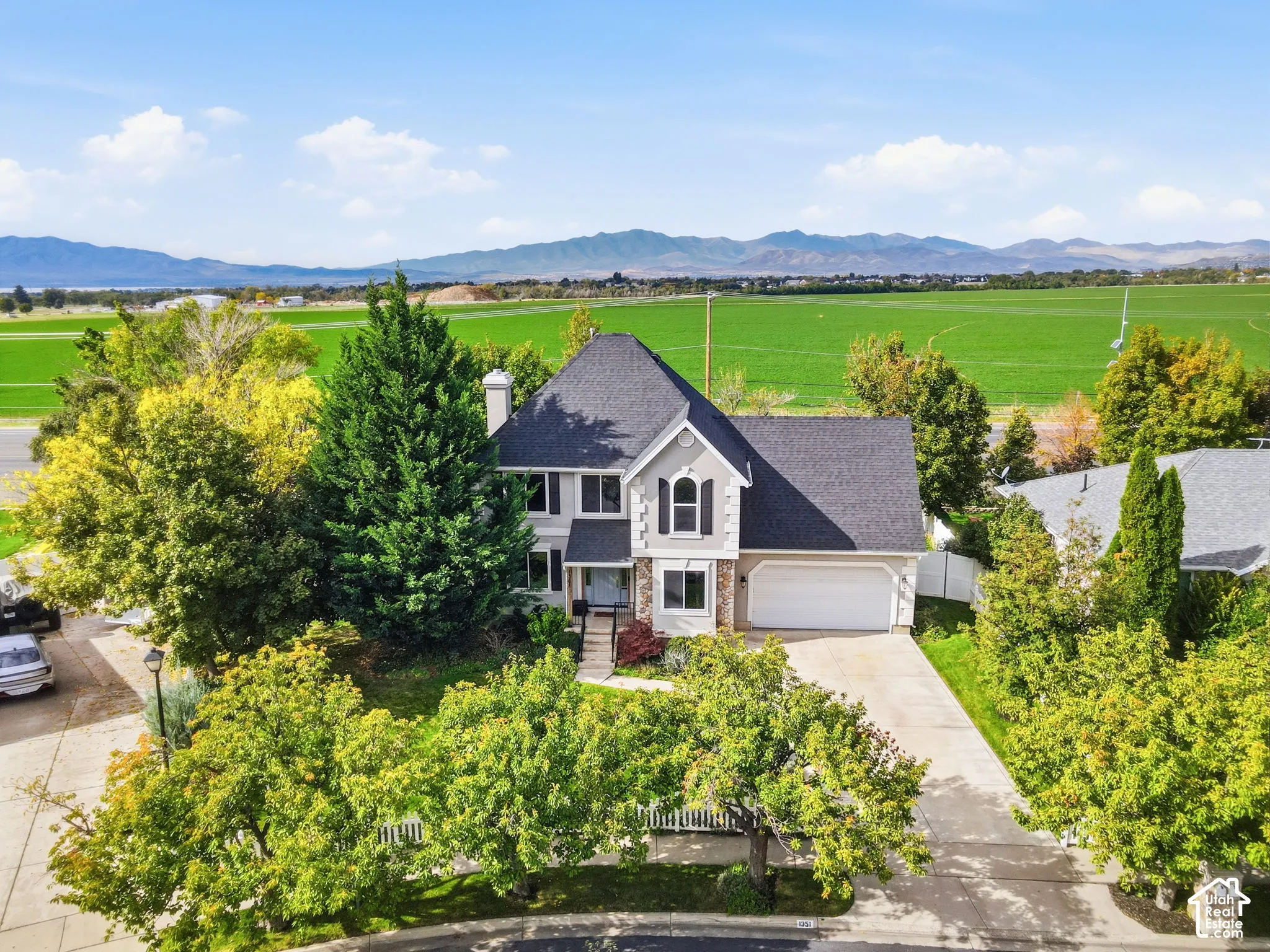 Two-story residence featuring a multi-gabled roofline, stone veneer accents, an attached two-car garage, and established landscaping set against a mountain backdrop
