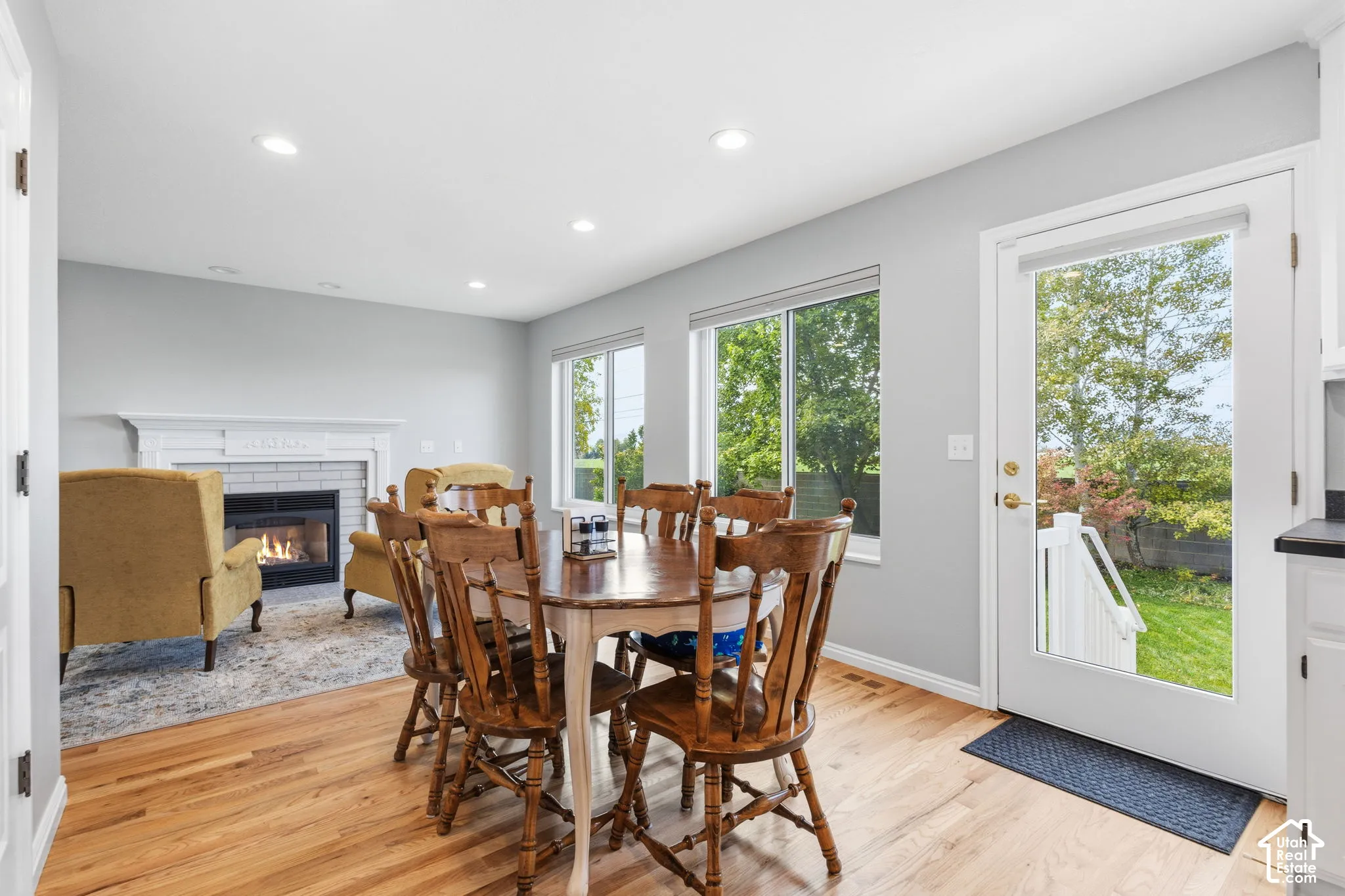 Wood-finish flooring, recessed lighting, fireplace with a painted mantel, and glass-paneled exterior door