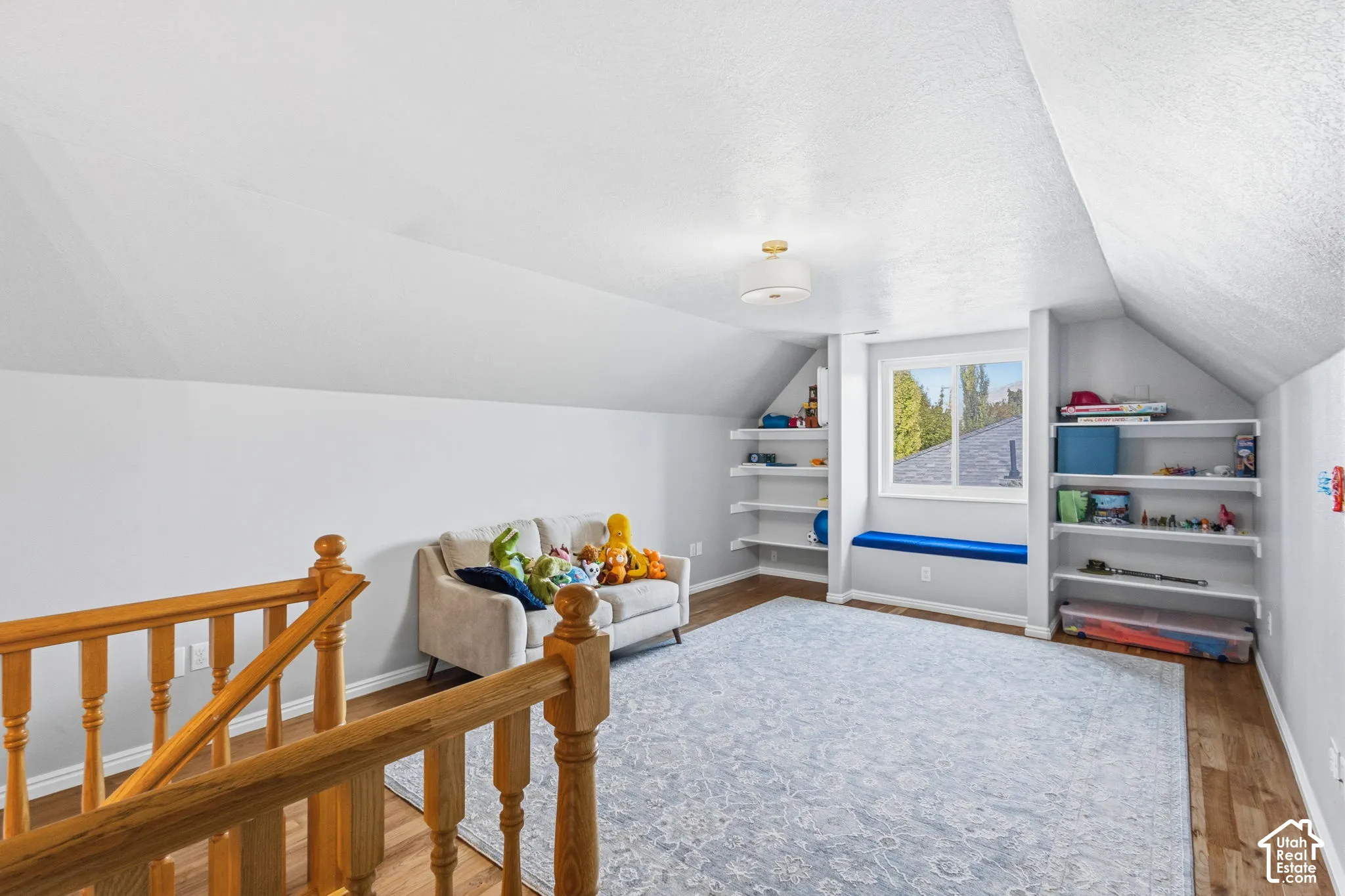 Wood-finish flooring, vaulted ceilings, built-in shelving, integrated window seat, and wood staircase railing