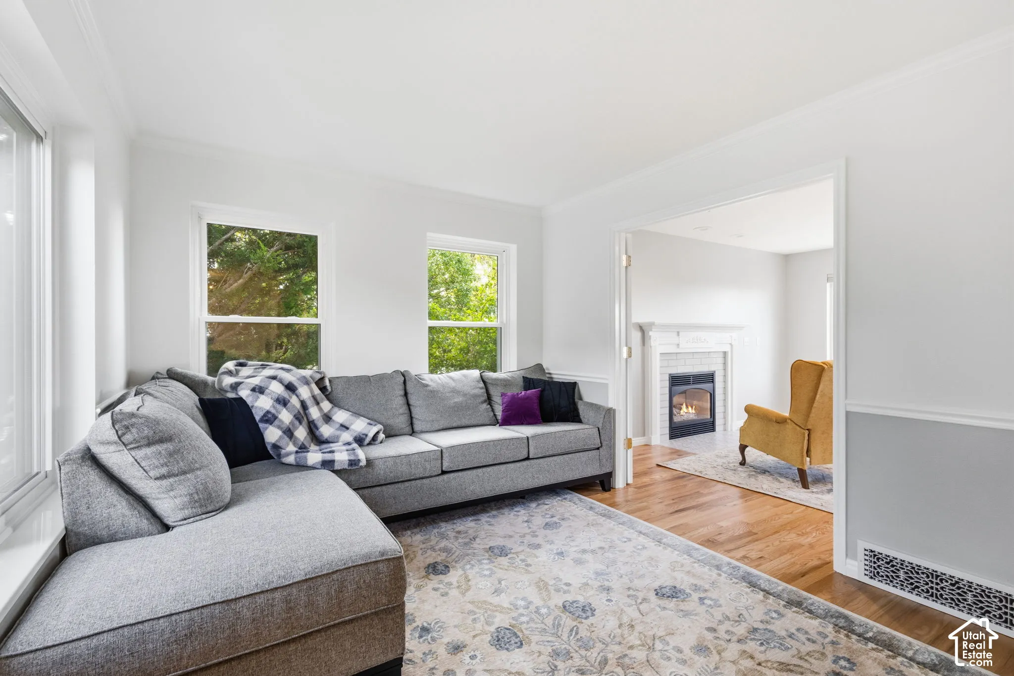 Hardwood flooring, dual-pane windows, crown molding, chair rail trim, and a fireplace with a decorative mantel
